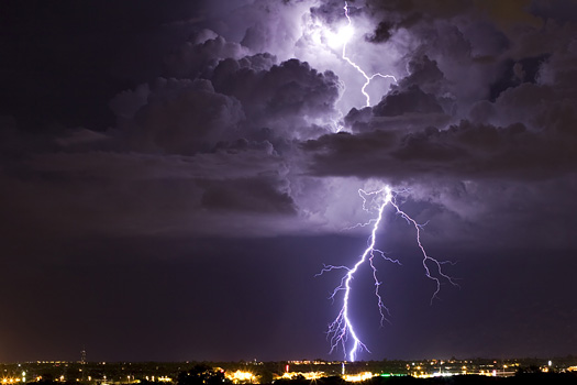 A thunderhead is illuminated by a bolt of lightning