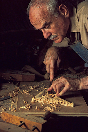 A woodworking man concentrating on an intricate piece of carving